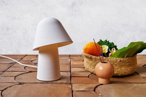 Lámpara y cesta de mimbre con frutas mediterráneas sobre baldosas de barro cocido artesanales