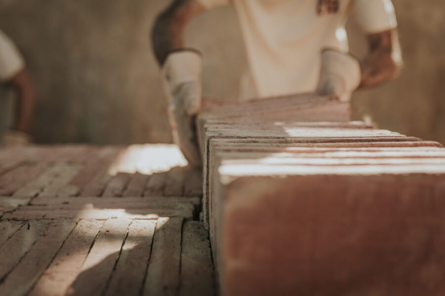 Maestro artesano colocando baldosas de barro cocido artesanales y ecológicas, un material que respeta los principios de la bioconstrucción