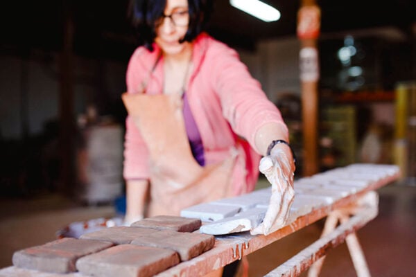 Neoartesania. Mujer trabajando con baldosas de barro cocido.
